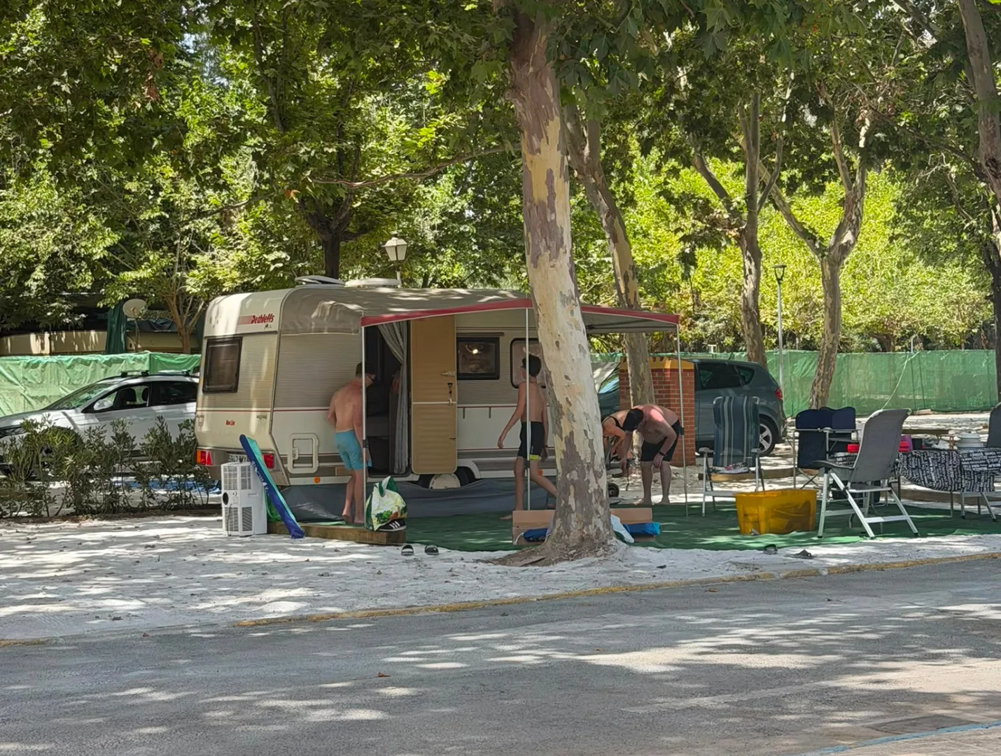 Caravana con familia en parcela arbolada